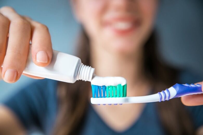 A person putting toothpaste on a toothbrush