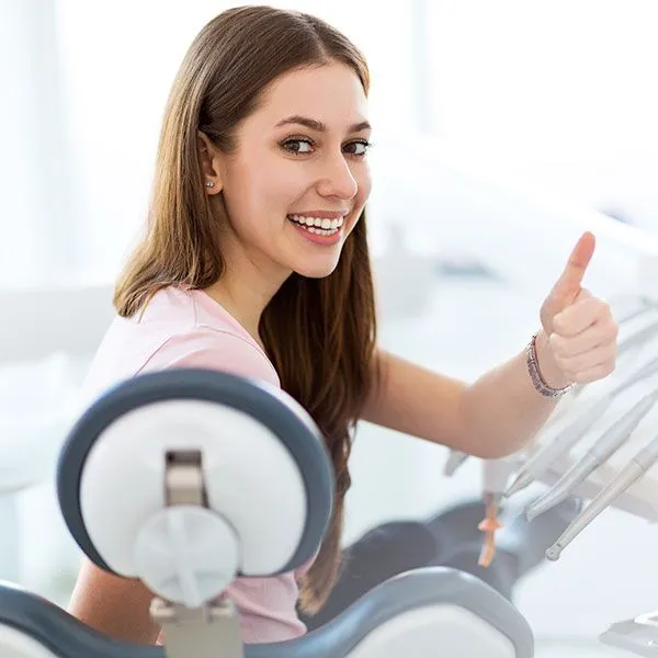 young woman smiling with thumbs after teeth cleaning in Scottsdale AZ