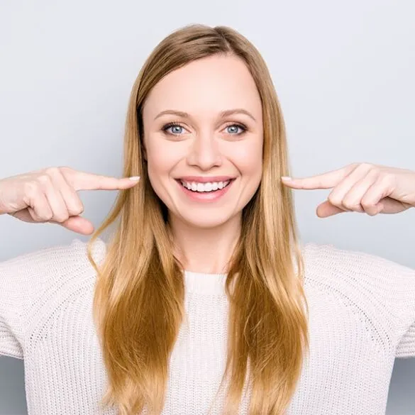 Women smiling pointing at face with both hands