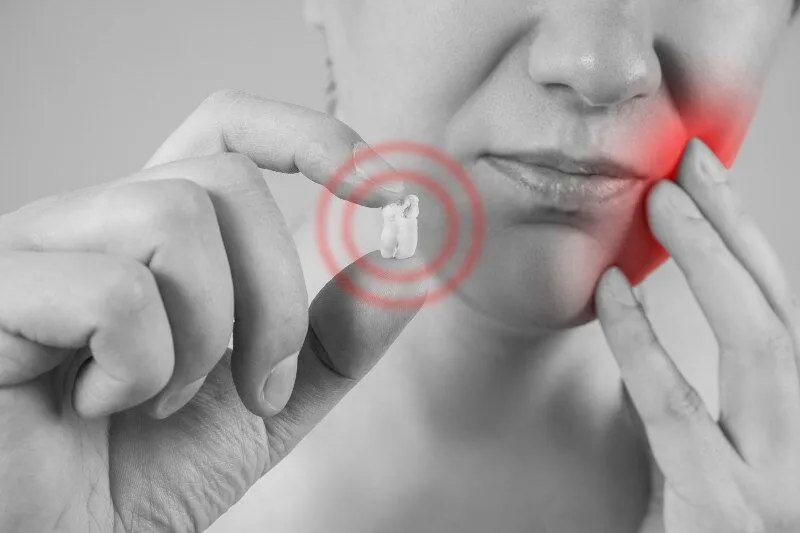 Woman holding tooth that was extracted
