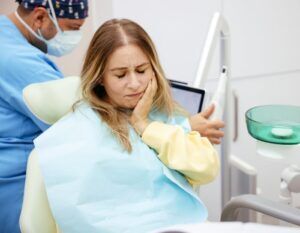 A woman holding her cheeks is receiving treatment for oral mucosal peeling in Scottsdale, AZ.
