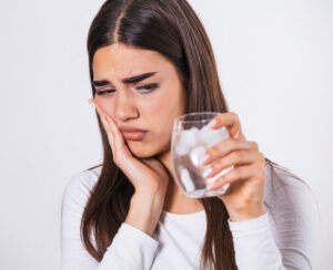A woman suffering from pain after a dental implant procedure in Scottsdale, AZ.
