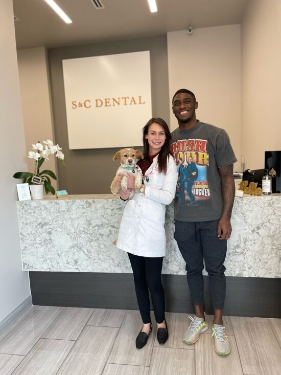 Dr. Bri holding a dog and posing with her patient at their clinic in Scottsdale, AZ