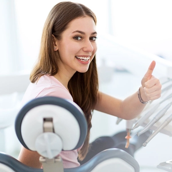 young woman smiling with thumbs after teeth cleaning in Scottsdale AZ