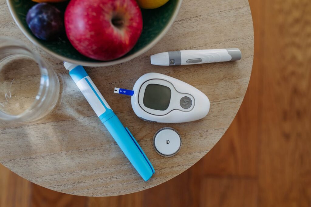 A bowl of fruit and a glucometer on a table