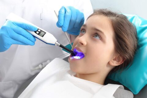 A dentist using a dental tool to check the teeth of a young child